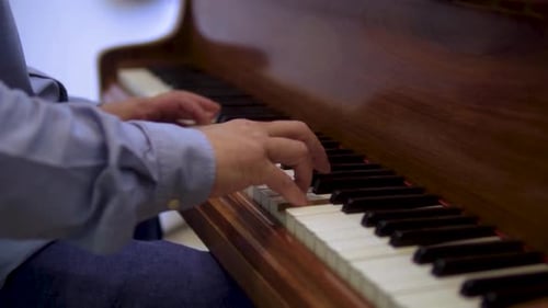 Pianist is performing on vintage brown wooden piano close up of hands playing notes creating melody