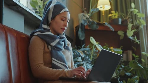 Muslim Businesswoman in Hijab Working on Laptop in Cozy Office