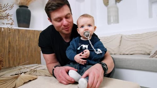 Father Holding Adorable Baby with Pacifier Indoors