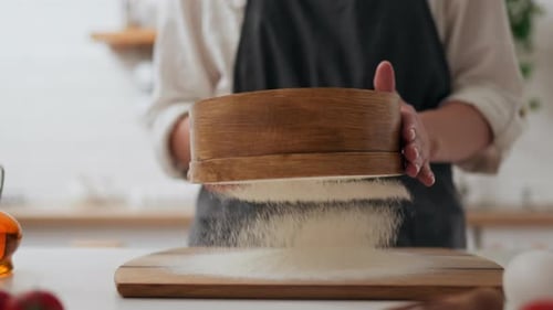 Der Prozess des Siebens von Mehl in der Küche. Die Bewegung der Hände von The Baker of The Cook Who