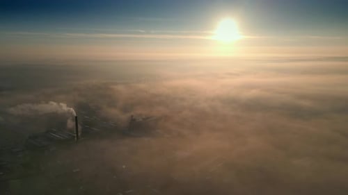 Fog Shrouded Cityscape with Factory Chimney at Sunrise