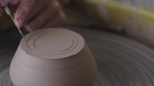 Un potier sculpte un morceau d'argile dans une tasse.