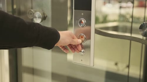 Hand Pushing Elevator Button in Modern Silver Building