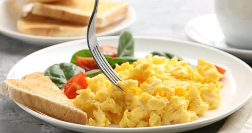 Scrambled Eggs with Toast and Spinach Being Eaten