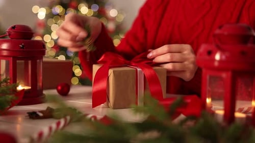 Woman wrapping Christmas gift at white table, closeup