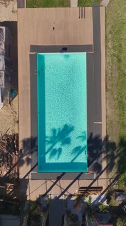 Vertical Video of a Luxurious Pool With Bright Blue Water Surrounded By a Scenic Garden Seen From