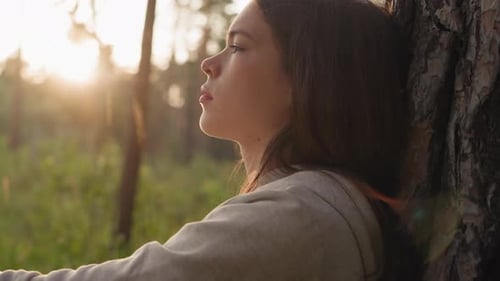 Sad Lady Rests Leaning on Tree Trunk