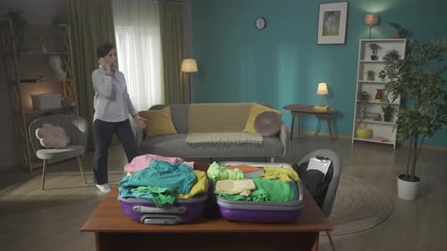 Woman Talking on Phone Near Open Suitcases
