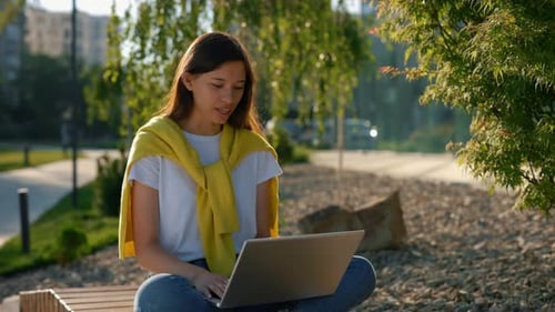 Smiling Woman Video-chatting on Laptop in Park