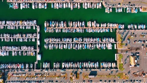 Docks with multiple yachts standing on the anchor. Boats at the backdrop of sea-green waterscape.