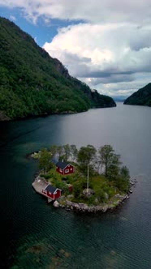 Island houses on lake surrounded by green mountains