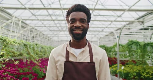 Smiling Man in greenhouse surrounded by flowers