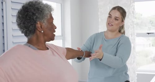 Woman Assists Senior with Arm Stretching Exercise