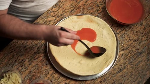 Chef Spreading Pizza Sauce on Pizza Crust