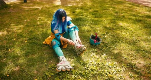 Teenager Roller Skater Girl with Blue Hair Puts on Rollerblades at Skate Park Training Hobby Active