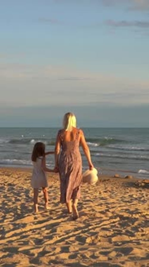 Mother and Daughter Walk on Sea Beach at Sunset Summer Vacation Travel Holiday