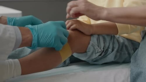Doctor Bandaging Little Girls Injured Leg in Hospital
