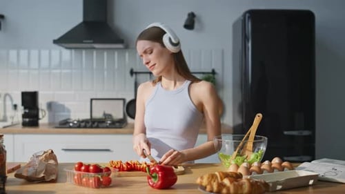 Woman Prepares Healthy Salad in Kitchen with Headphones