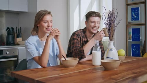 Smiling Couple Enjoying Breakfast Together in Kitchen