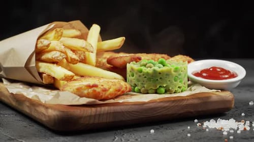 Steaming fish, chips, and peas served on a wooden board
