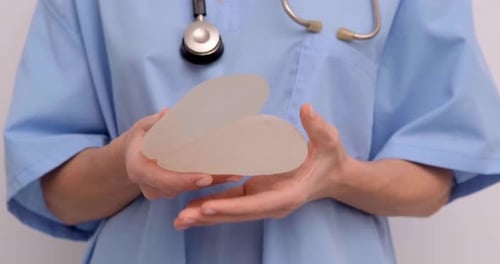 Doctor Holding Two Silicone Breast Implants Close Up
