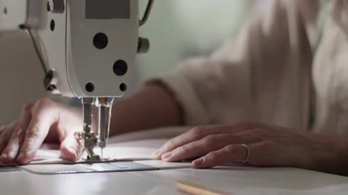 Female Tailor Stitching Fabric on Sewing Machine in Studio