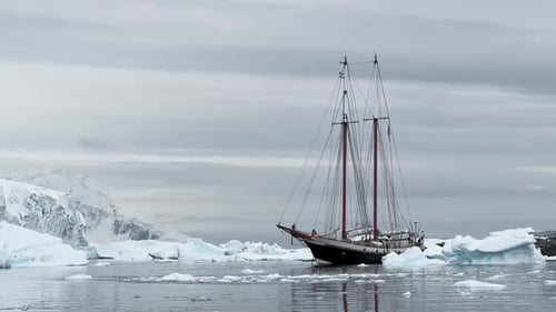 Retro Style Sailing Schooner During the Huge Iceberg in the Antarctic Peninsula at the South Pole