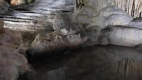Giant limestone underground cave with pure white stalactites and stalagmites. Water flowing from the