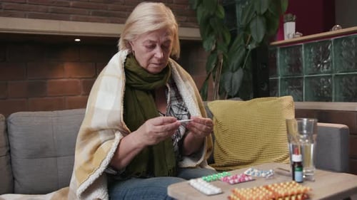 Sick Woman Checking Temperature on Couch At Home