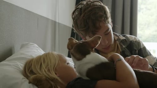 Girl and Teen Petting Dog on Bed