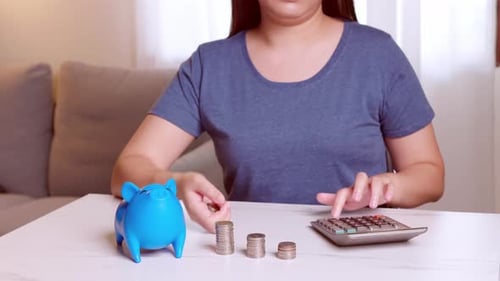 Women using calculators and putting coins in a piggy bank, saving money concept. Future needs loan e