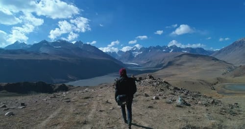 Earth Aerial: Solo Backpacker exploring a majestic mountain landscape. Unexplored and wild places of