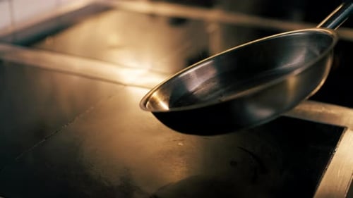 in Professional Kitchen Pours Oil Into a Small Frying Pan on the Hot Stove