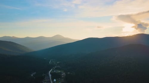 Cenário incrível com pequenas casas de vila entre picos nebulosos e escuros cobertos de pinheiros da floresta