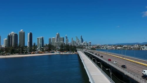 Luftaufnahme einer neu errichteten Fußgängerbrücke über Wasser, die in eine Stadt mit hoch aufragendem Himmel führt