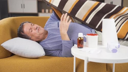 Uncomfortable man covers himself with blanket on couch