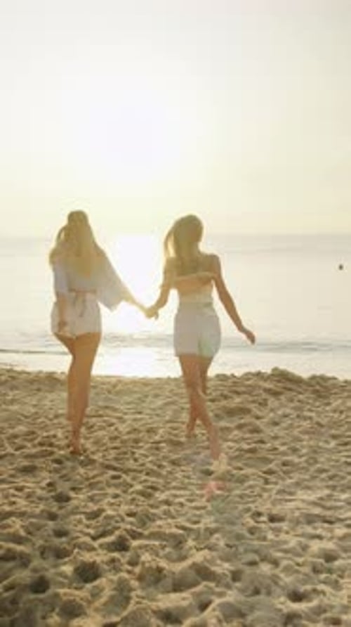 Two Female Friends Joyfully Running Along the Beach at Sunset Creating Lasting Memories on a Warm