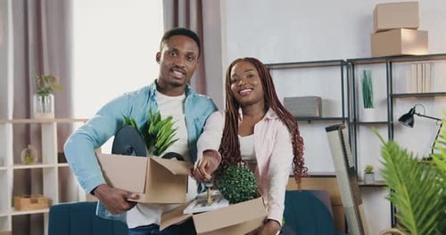 Smiling couple man and woman looking at camera with keys to their new dwelling after relocation