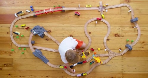 Child Plays with Toy Train and Cars on Floor
