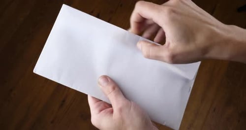 Hands Opening a White Mailing Envelope