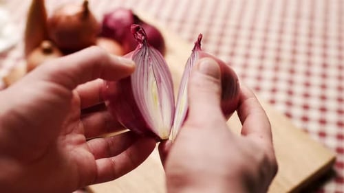 Manos que sostienen dos mitades de cebolla morada