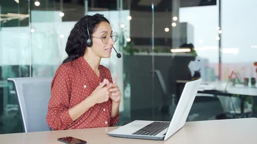 Woman with Headset Talking and Typing on Laptop