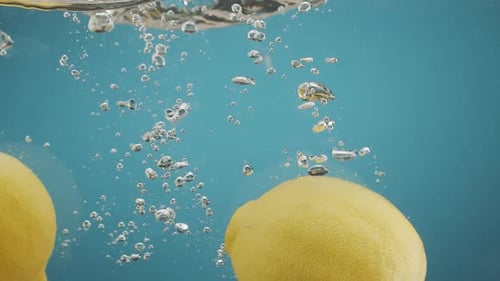 Lemons Dropping Into Water With Bubbles