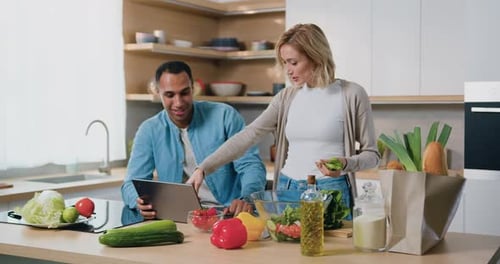 Familia feliz y atractiva cocinando ensalada juntos en Modern Kitchen.