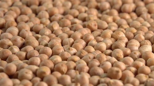 Dry chickpeas or dried garbanzo beans rotating on plate background side view. Ingredient