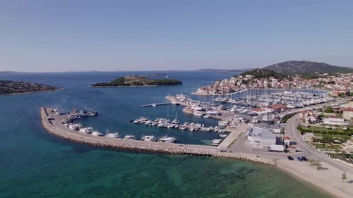 Aerial view of coastal town with marina, boats, and island, Croatia.