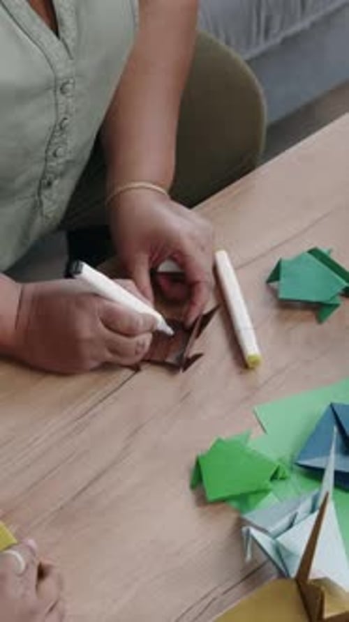 Hands of Woman and Kids Colouring Paper Origami Frogs with Markers