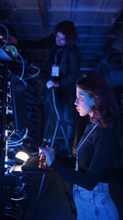 Woman Types on Server Keyboard in Dim Data Center