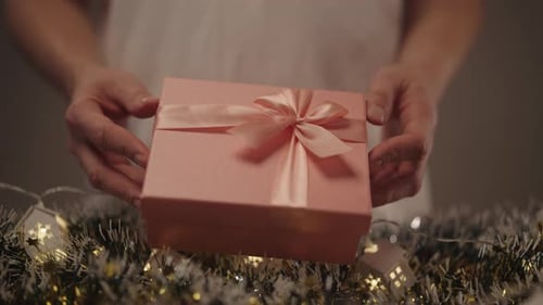 Woman Holding Pink Gift Box With Ribbon Indoors