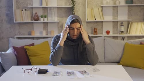 Worried Man Counting Money at Table Indoors